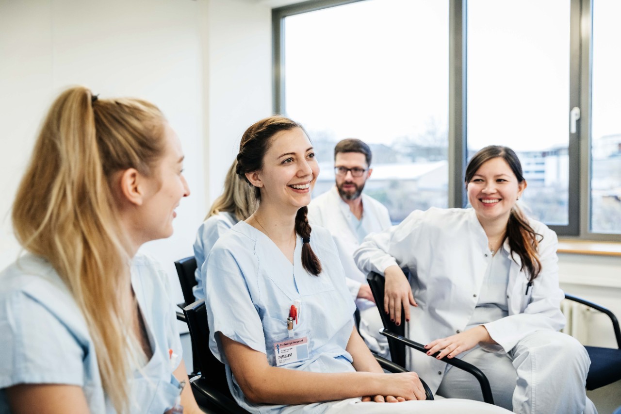 A group of medical students laughing with each other during a teaching seminar at the hospital.